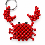 Red beaded crab charm laid flat with raised claws, black bead eyes and a silver-tone ring