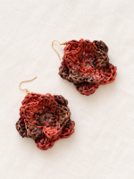 Pair of raffia flower earrings in warm red and brown tones with gold-tone hooks