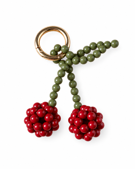 Burgundy beaded cherry bag charm with olive-green stems and a gold-tone ring on a white background.