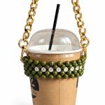 Olive green KAFEDAKI beaded cup carrier with a gold-tone chain holding a takeaway coffee cup