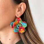 Colorful raffia flower statement earring in red, yellow, turquoise and green worn on the ear