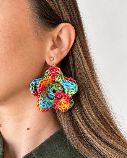 Colorful raffia flower statement earring in red, yellow, turquoise and green worn on the ear