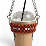 ONE MORE beaded cup carrier with reddish-brown beads and a silver-tone chain holding a takeaway coffee cup