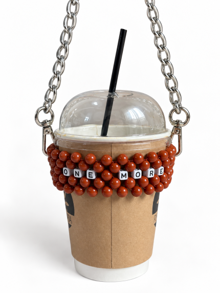 ONE MORE beaded cup carrier with reddish-brown beads and a silver-tone chain holding a takeaway coffee cup