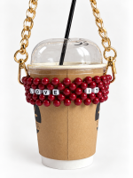 Burgundy LOVE IT beaded cup carrier with a gold-tone chain holding a takeaway coffee cup
