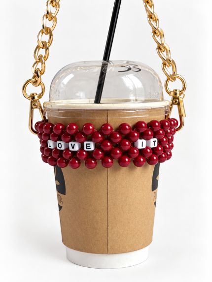 Burgundy LOVE IT beaded cup carrier with a gold-tone chain holding a takeaway coffee cup