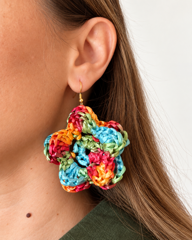 Colorful red, yellow, turquoise and green raffia flower earring worn with a gold-tone hook