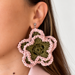 Pink and olive green open bloom raffia flower earring worn on the ear with a silver-tone fastening