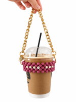 Hand holding a takeaway coffee cup in a dusty pink MUST HAVE beaded carrier with a gold-tone chain